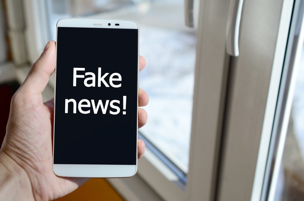 A person sees a white inscription on a black smartphone display that holds in his hand. Fake news!